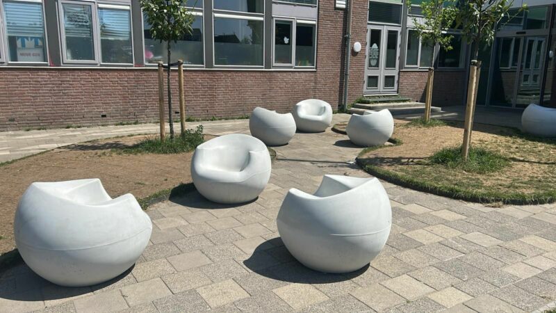 Drie witte design betonnen zitelementen uit de Stool collectie op een schoolplein
