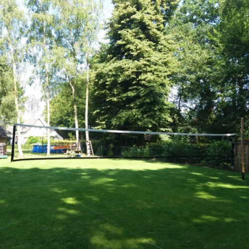 Schoolvolleybalnet met geïntegreerde houten spanstokken voor een stabiele netspanning. Het net wordt gemonteerd tussen volleybalpalen; de afgebeelde houten palen worden niet meegeleverd