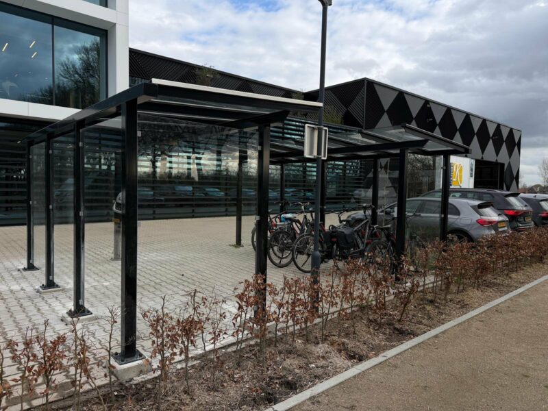 Twee fietsoverkappingen model City met glazen wanden en dak van veiligheidsglas geplaatst bij Kempen Cladding in Bergeijk