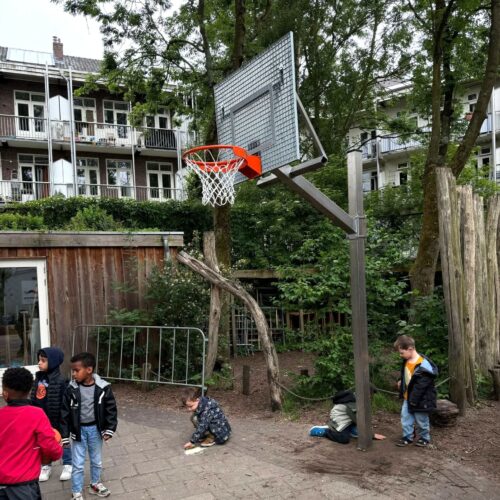 Verstelbare basketbalpaal Rothe+ 34 Verstelbare RVS basketbalpaal met antivandaal basketbalbord geplaatst op een schoolplein in Amsterdam