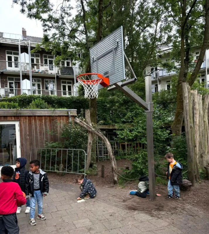 Verstelbare RVS basketbalpaal met antivandaal basketbalbord geplaatst op een schoolplein in Amsterdam