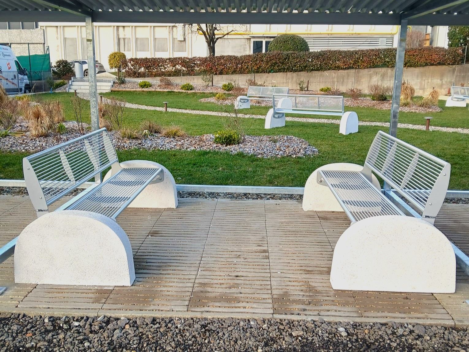 Parkbank Tauri Concrete 8 Parkbanken model Tauri Concrete met betonnen zijsteunen geplaatst in een groene parkomgeving.