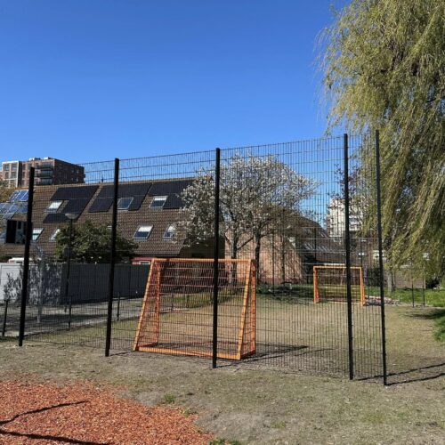 Voetbaldoeltjes model TRD300 104 trapveldje met 2 oranje stalen voetbaldoelen en geluidsarme ballenvangers buiten geplaatst