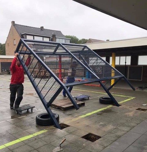 Voetbaldoeltjes model TRD300 53 Twee monteurs plaatsen een TRD300 voetbaldoel door het doel in de uitgegraven funderingsgaten op een schoolplein te kantelen.