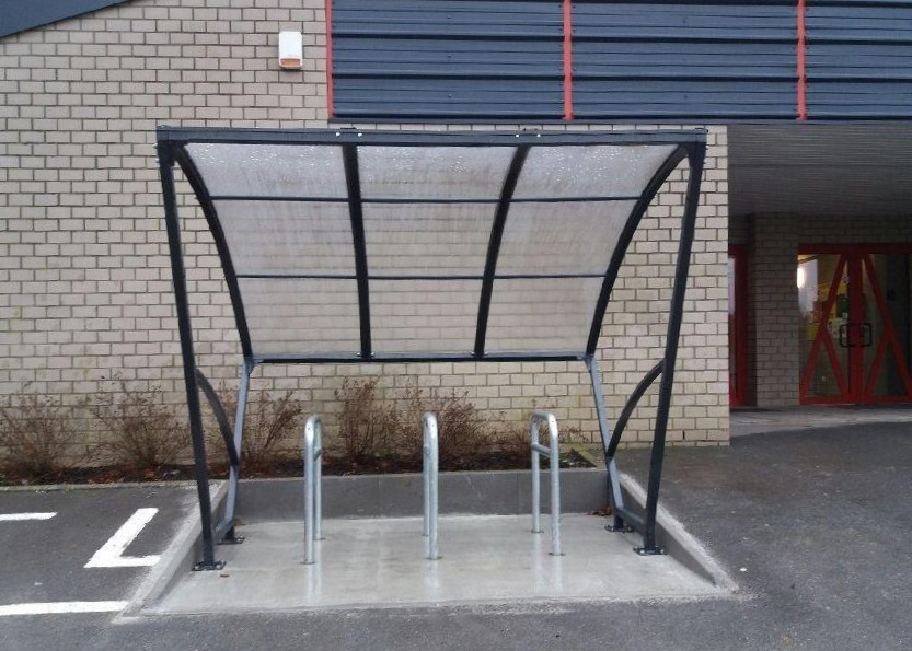 Fietsoverkapping Velo - Compact en Voordelig 1 Transparante fietsoverkapping 2.5 meter met fietsnietjes op betonplaat.