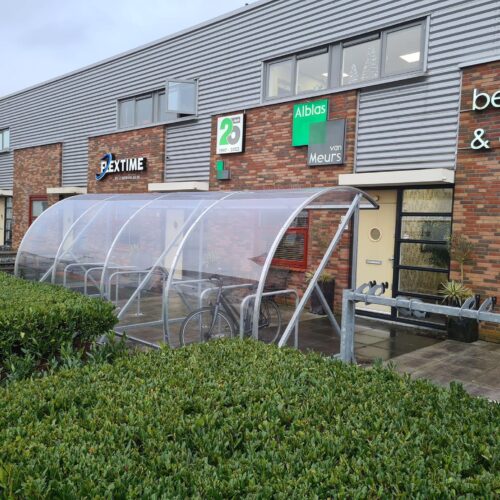 Fietsoverkapping BF1000 – Halfrond & Transparant 242 Fietsoverkapping bij een gebouw Lengte 6 meter