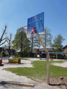 Basketbalpaal Rothe Fixed. Hier is gekozen voor een poedercoating van het basketbalbord in de kleuren van de school, zodat de basketbalpaal keurig aansluit bij het geheel.