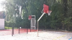 Basketbalpaal model Rothe Fixed, voorzien van rood gepoedercoat geluids- en vandalisme-arm basketbalbord.