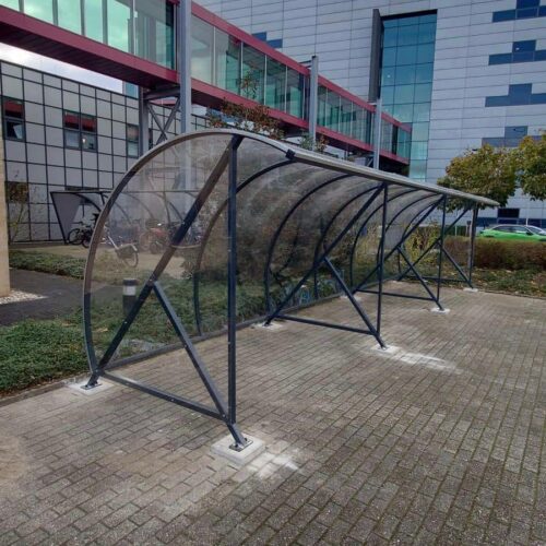 Fietsoverkapping BF1000 – Halfrond & Transparant 241 Fietsoverkapping bij een modern gebouw.