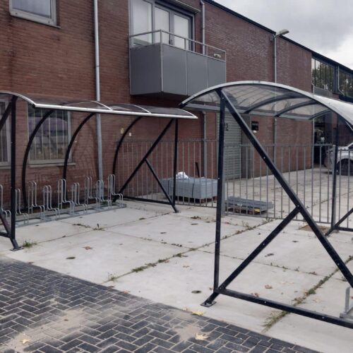 Fietsoverkapping BF1000 – Halfrond & Transparant 239 Fietsoverkappingen naast een gebouw. Met fietsenrekken.