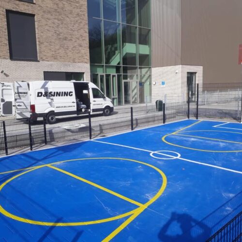 Sportvloercoating 54 Deze mini multi sportkooi is uitgevoerd met een blauwe rolcoating > Granuplast met witte voetbal belijning en gele basketbalbelijning. Locatie Amsterdam.