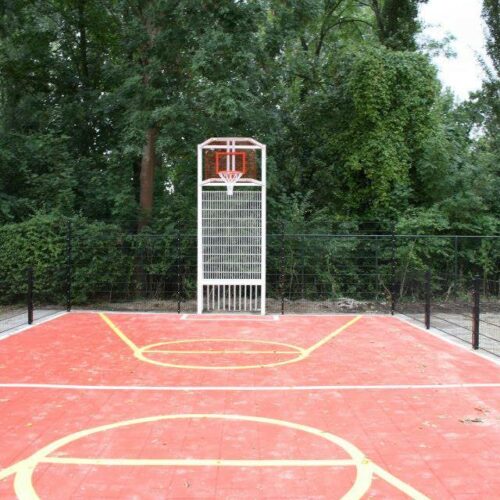 Sportvloercoating 64 Pannakooi met basketbal en een rood gecoate speelvloer en witte voetbal-belijningen en gele basketbal-belijningen bij school in Amsterdam.