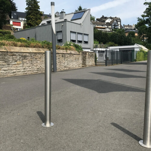 Parkeerpalen rvs204 35 Drie RVS afzetpalen met voetplaat op asfalt in voetgangersgebied – duurzame terreinbeveiliging