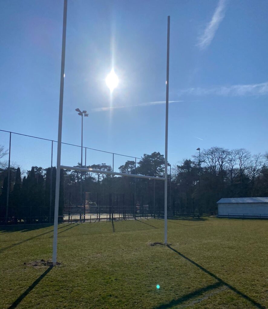Hoe hoog moet een ballenvanger zijn? Alles over hoogte, netten, constructie en fundering 4 Rugbygoal met op de achtergrond een ballenvanger van 6m hoog met net