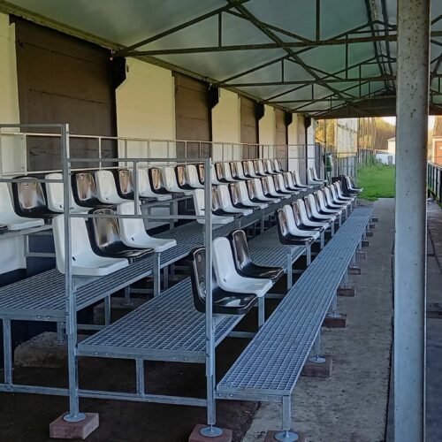 Modulaire sport- tribunes 91 Onze mini tribune in Belzele (België) 3 zitrijen, lengte 13.5 meter onder een bestaande overkapping geplaatst. OOk deze is 25cm verhoogd.