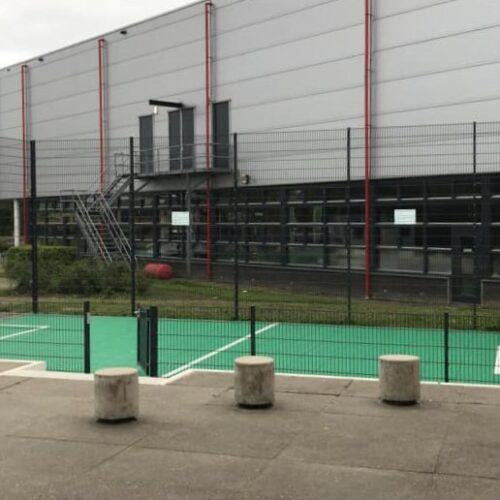 Sportvloercoating 41 Onze Premium voetbalkooi met basketbal, voorzien van een groene Granuplast rolcoating en witte belijningen.