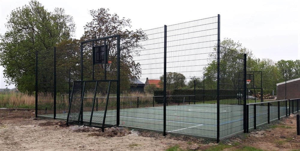 Waterdoorlatend beton 10 Een voetbalkooi met basketbal uit onze Premium-serie voorzien van een drainbeton speelvloer met groene coating en belijning.
