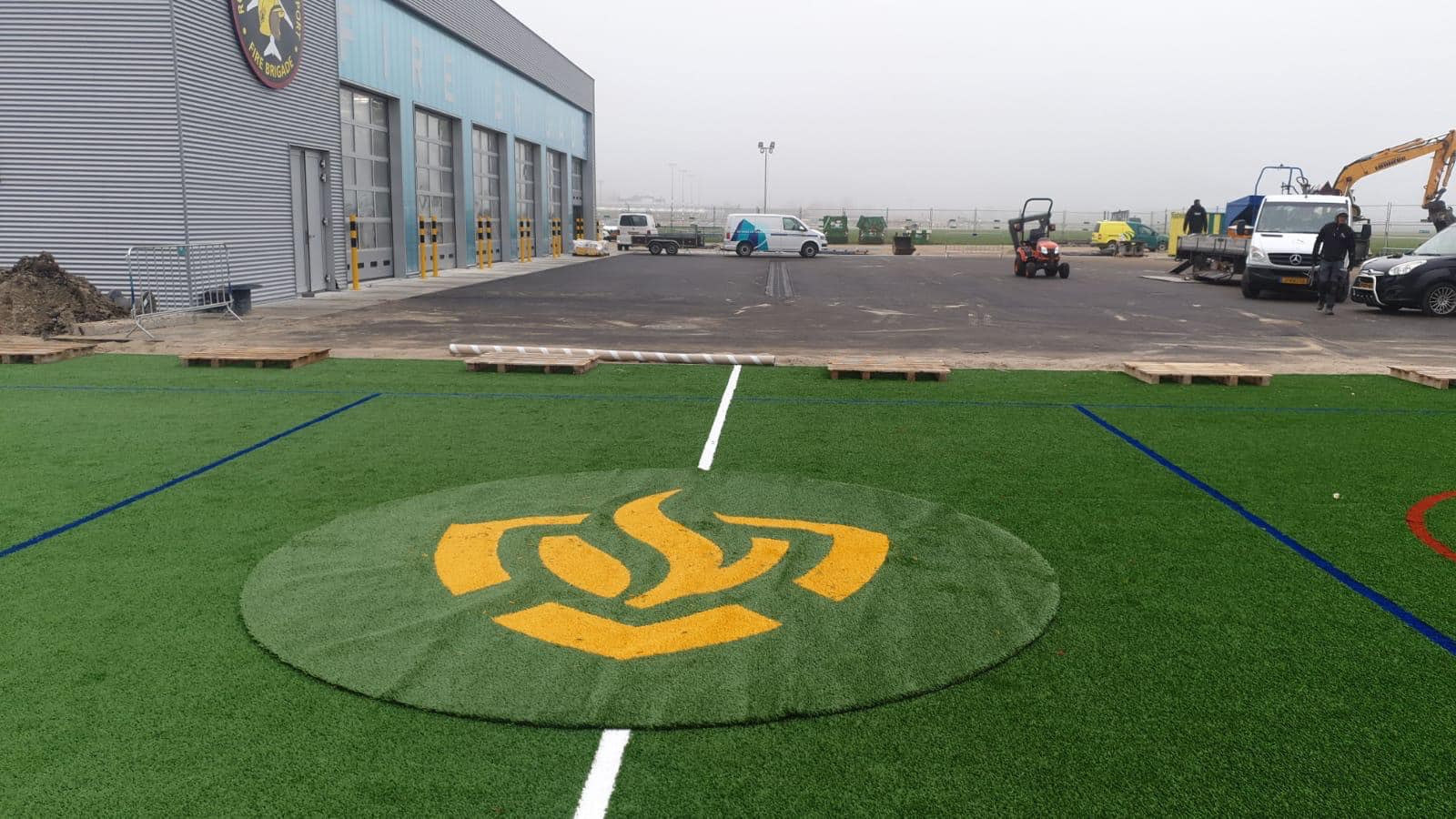 Kunstgras speelvloeren 30 Aanleg van een grote voetbalkooi met LSR24mm kunstgras met een ingelegd logo. Locatie Rotterdam met het logo van de brandweer (airport)