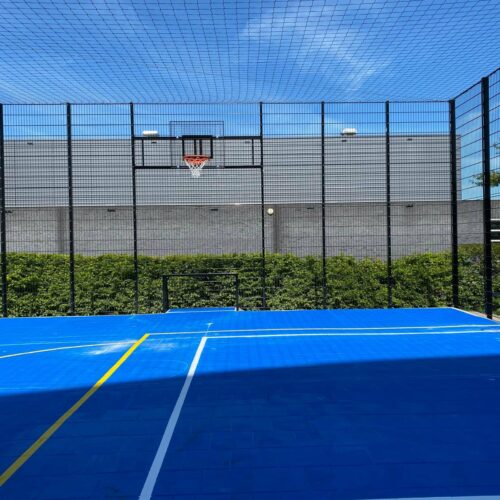 Sportvloercoating 63 Voetbalkooi met een blauwe Granuplast-coating met voetbal en basketbalbelijningen.