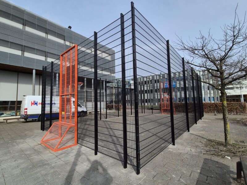 Geluidsarme overdekte pannakooi met basketbalvoorzieningen op schoolplein