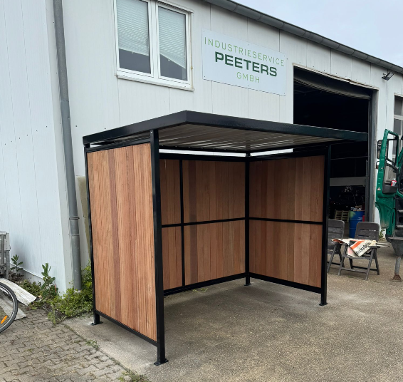 Fietsoverkapping Nordic geplaatst bij Group Peeters in Nörvenich (Duitsland) 2 Volledig gemonteerde fietsoverkapping Nordic met FSC-hardhout en zwart frame RAL 9005 bij Group Peeters in Duitsland, Nörvenich