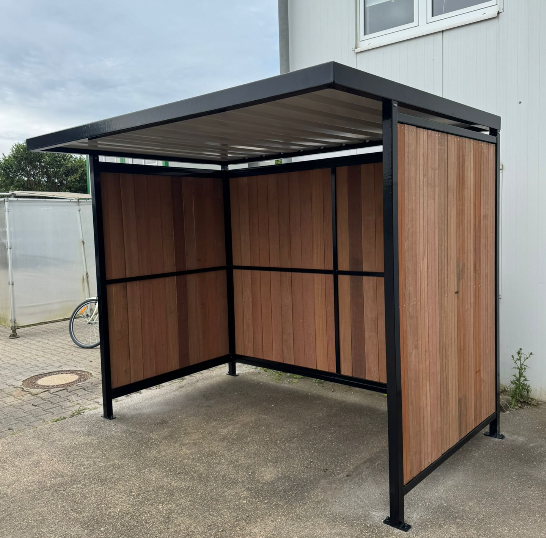 SKWshop aanwezig bij de Haring Party 2026 van Martini Business 10 Hoekaanzicht van Fietsoverkapping Nordic met FSC-hardhouten wanden en zwart gepoedercoat frame RAL 9005 geplaatst in Nörvenich voor group Peeters