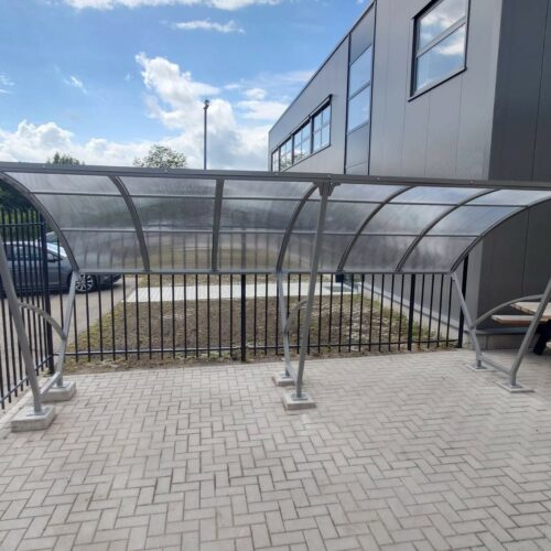 Fietsoverkapping Velo - Compact en Voordelig 28 Fietsoverkapping model Velo van 5 meter met gecoat frame en polycarbonaat dak op bedrijfsterrein in Varsseveld.