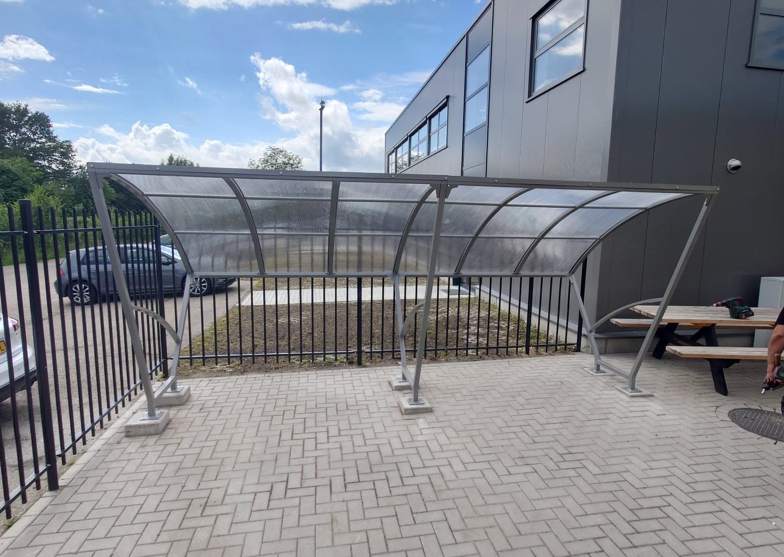 Fietsoverkapping Velo - Compact en Voordelig 14 Fietsoverkapping model Velo van 5 meter met gecoat frame en polycarbonaat dak op bedrijfsterrein in Varsseveld.