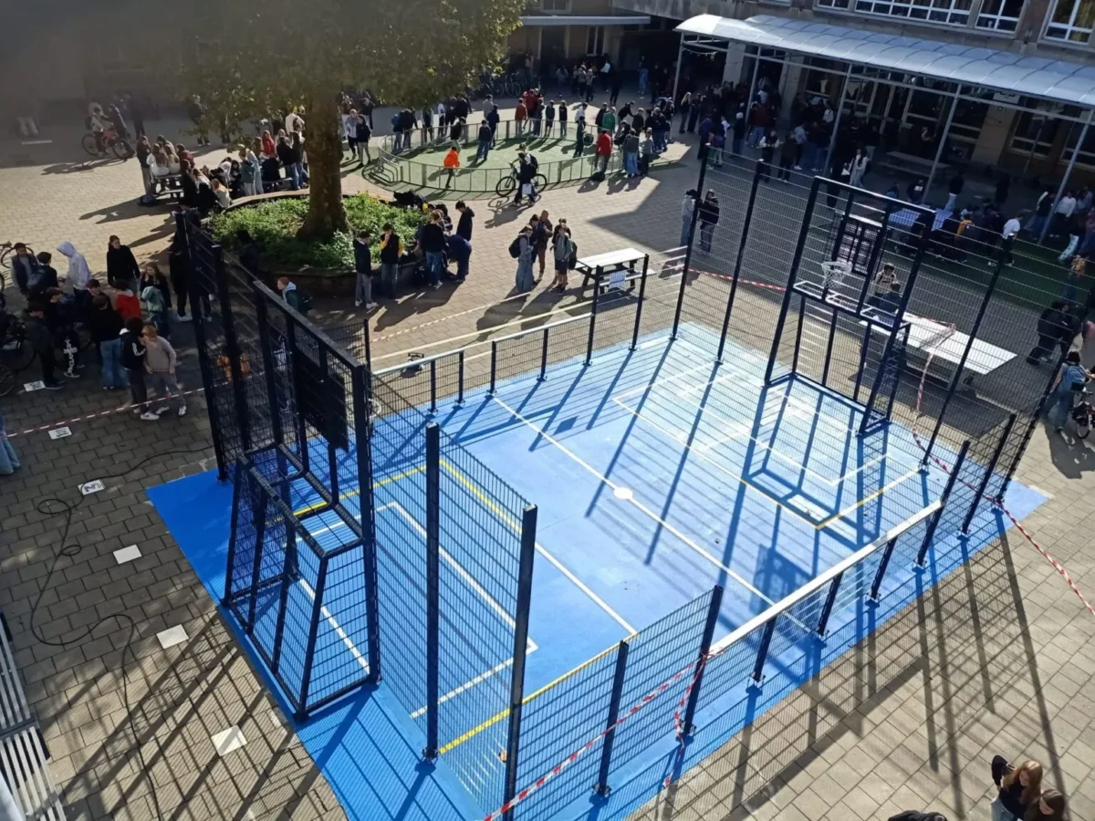 Pannakooi plaatsen? Een complete gids voor een veilige, duurzame én geluidsbewuste sportvoorziening 1 Geluidsarme pannakooi met basketbalvoorzieningen en blauwe sportvloer op een schoolplein in Vlaanderen.