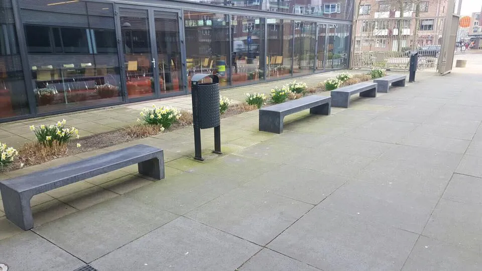 Brandveilige bankjes en parkbanken bij woongebouwen: wat zegt het Bbl? 6 Betonnen parkbanken geplaatst bij de entree van een schoolgebouw