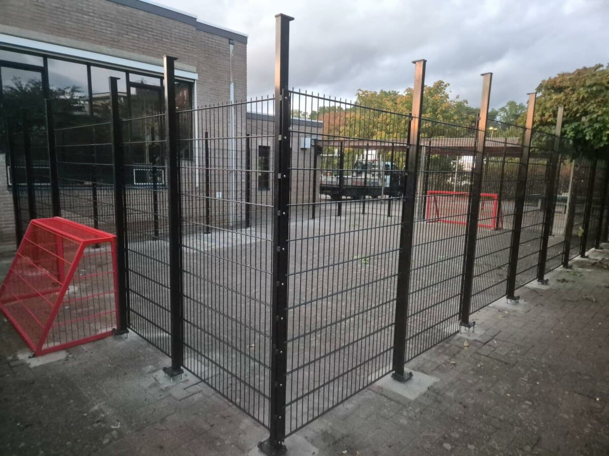 Twee maatwerk pannakooien geleverd en gemonteerd in Genk en bij Delfland 2 Pannakooi op het schoolplein van De Padvinder in Genk, met 2 meter hoge zwarte wanden en twee geïntegreerde rode voetbaldoelen van 200 × 100 cm.